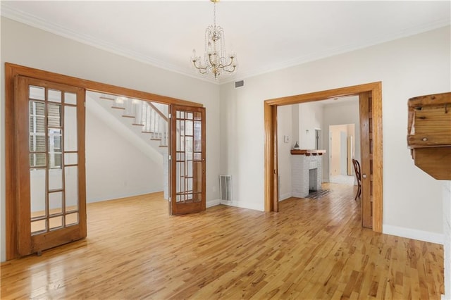 2031 General Taylor St, New Orleans, LA 70115 - spare room with a chandelier, stairs, light wood-style floors, crown molding, and baseboards