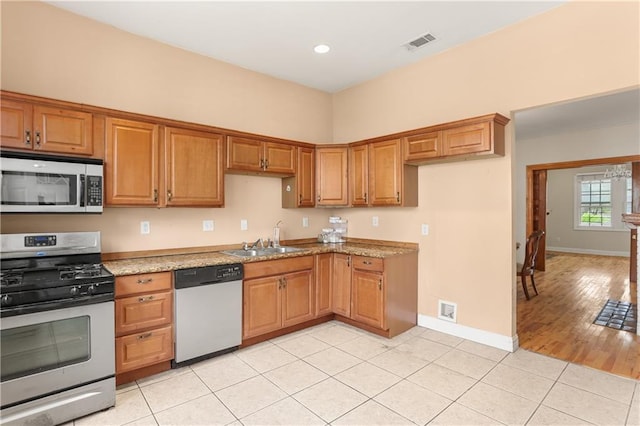 2031 General Taylor St, New Orleans, LA 70115 - kitchen with appliances with stainless steel finishes, a sink, brown cabinetry, light tile patterned floors, and baseboards