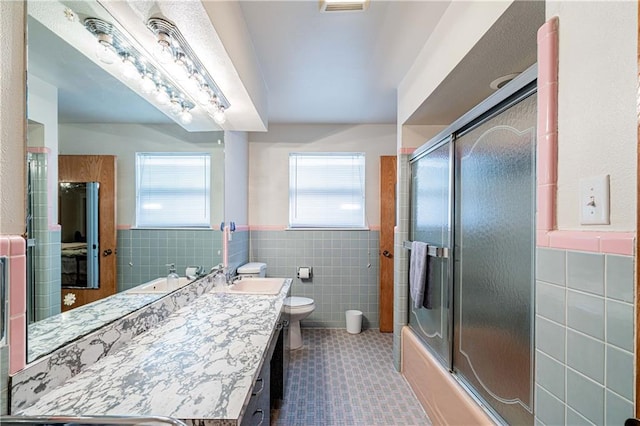 966-968 Allen Toussaint Blvd, New Orleans, LA 70124 - bathroom featuring tile walls, wainscoting, vanity, toilet, and bath / shower combo with glass door