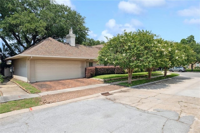 5542 Marcia Ave, New Orleans, LA 70124 - view of front of home featuring an attached garage, driveway, a chimney, and brick siding