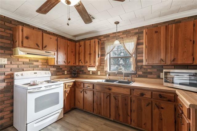 5679 Jean Lafitte Blvd, Jean Lafitte, LA 70067 - kitchen featuring electric range, under cabinet range hood, a sink, stainless steel microwave, and light countertops