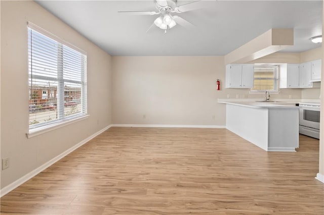 2713 Independence St, Metairie, LA 70006 - kitchen with white electric range, light wood-style flooring, light countertops, a peninsula, and plenty of natural light