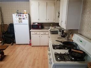 212 Short St, Amite, LA 70422 - kitchen featuring white appliances, light countertops, a sink, white cabinets, and light wood-style flooring