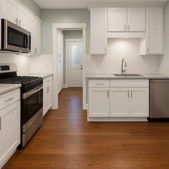 5621 Tchoupitoulas St, New Orleans, LA 70115 - kitchen featuring stainless steel appliances, tasteful backsplash, white cabinets, dark wood-style flooring, and light stone counters