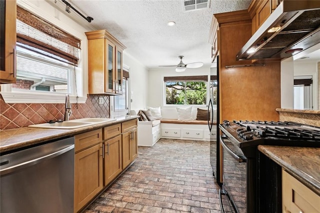 4517 Bissonet Dr, Metairie, LA 70003 - kitchen with stainless steel dishwasher, gas range, a sink, under cabinet range hood, and brick floors