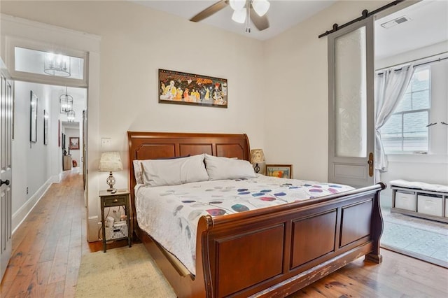 205 S Norman C Francis Pkwy, New Orleans, LA 70119 - bedroom featuring light wood-style floors, a chandelier, ceiling fan, baseboards, and a barn door