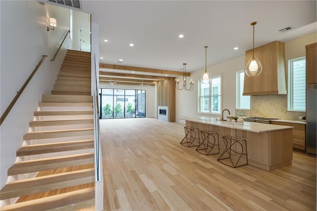 7104 Coliseum St, New Orleans, LA 70118 - kitchen with light wood finished floors, light countertops, a kitchen breakfast bar, custom range hood, and recessed lighting