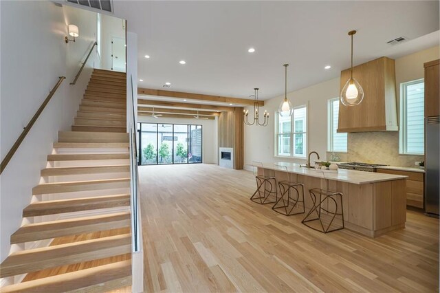 7104 Coliseum St, New Orleans, LA 70118 - kitchen with light wood-type flooring, light countertops, a breakfast bar area, recessed lighting, and a kitchen island with sink