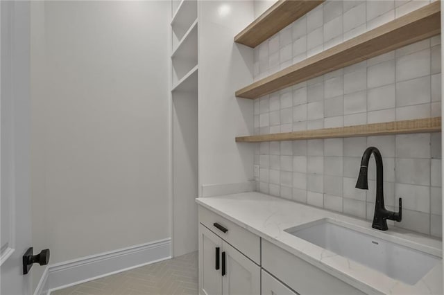 7104 Coliseum St, New Orleans, LA 70118 - interior space featuring open shelves, a sink, decorative backsplash, light stone countertops, and brick patterned flooring