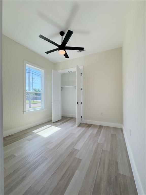 1421 David Dr, Metairie, LA 70003 - unfurnished bedroom featuring light wood-style floors, baseboards, a ceiling fan, and a closet