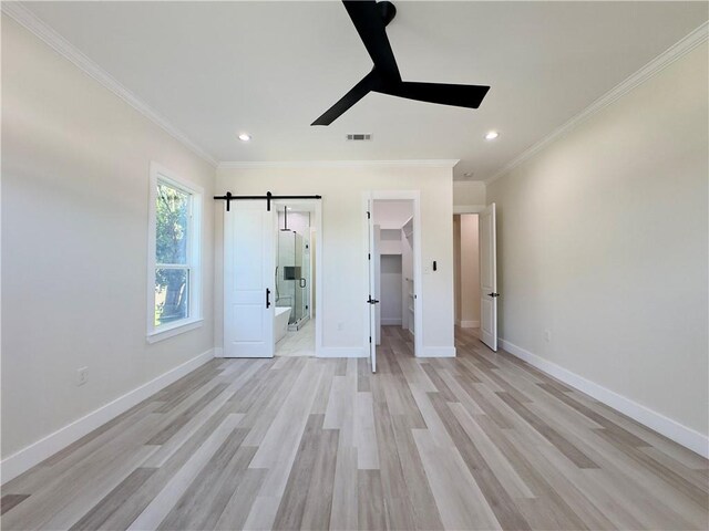 1421 David Dr, Metairie, LA 70003 - unfurnished bedroom with a walk in closet, ornamental molding, light wood-style floors, recessed lighting, and a barn door