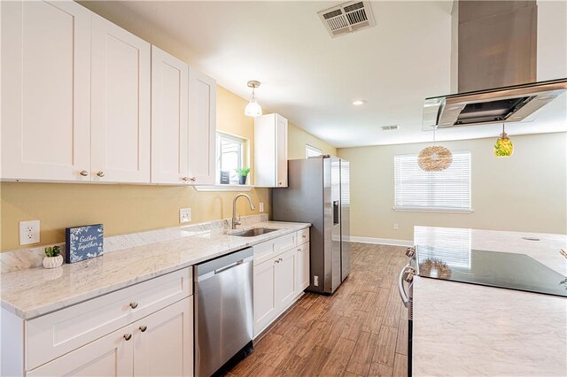 234 Murray Hill Dr, Destrehan, LA 70047 - kitchen featuring appliances with stainless steel finishes, a sink, white cabinets, light wood-style floors, and decorative light fixtures