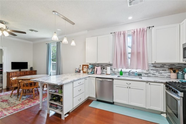 220 Moss Ln, River Ridge, LA 70123 - kitchen with appliances with stainless steel finishes, a sink, a peninsula, a textured ceiling, and dark wood-style flooring