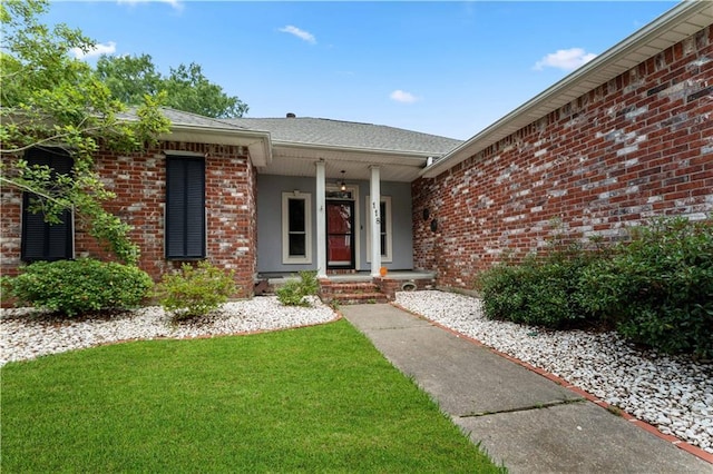 118 Windward Passage St, Slidell, LA 70458 - doorway to property featuring brick siding, a lawn, covered porch, and roof with shingles
