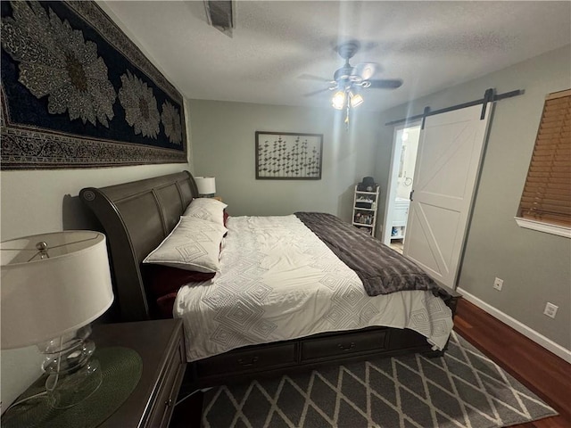 6035-37 Colbert St, New Orleans, LA 70124 - bedroom featuring wood finished floors, a barn door, baseboards, ceiling fan, and a textured ceiling