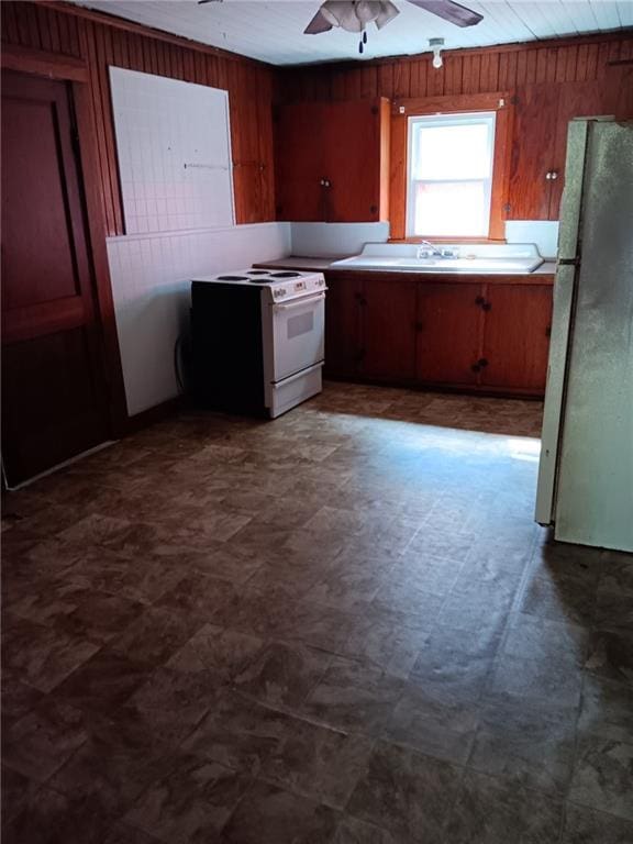802 Varnado St, Franklinton, LA 70438 - kitchen with freestanding refrigerator, white electric stove, wood walls, ceiling fan, and dark flooring