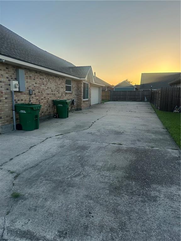 2227 Pine Valley Dr, La Place, LA 70068 - rear view of property with concrete driveway, a garage, brick siding, and roof with shingles