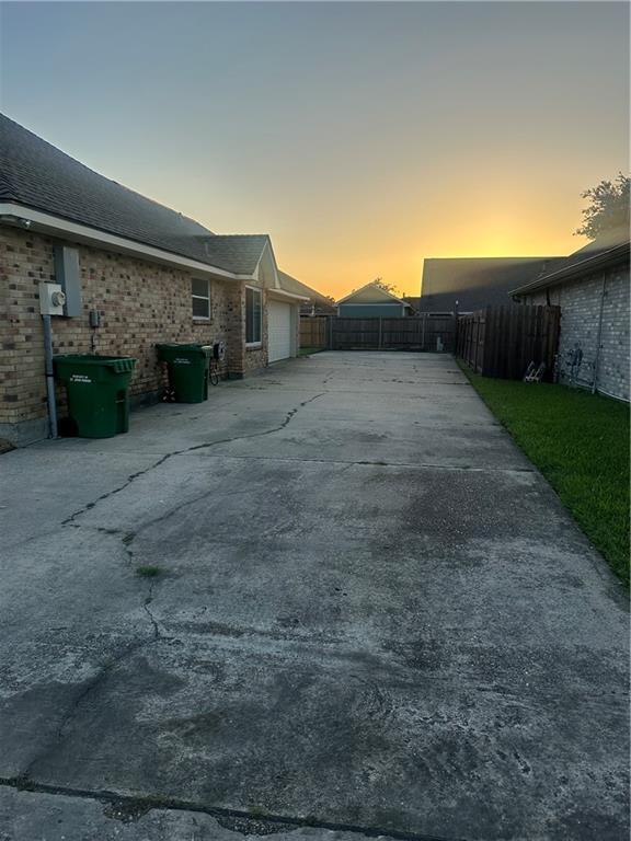 2227 Pine Valley Dr, La Place, LA 70068 - patio terrace at dusk featuring concrete driveway and a garage