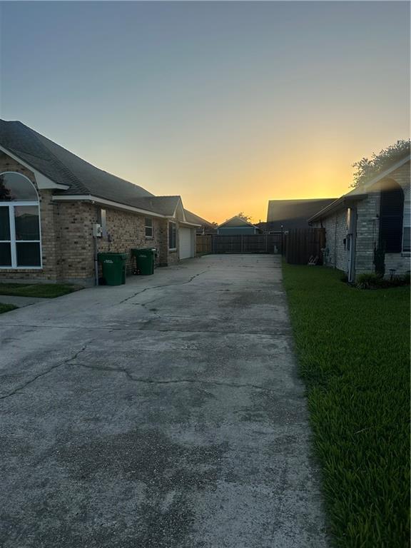 2227 Pine Valley Dr, La Place, LA 70068 - property exterior at dusk featuring concrete driveway, an attached garage, and brick siding