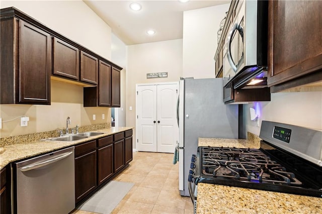 724 Fairfield Loop, Slidell, LA 70458 - kitchen featuring stainless steel appliances, a sink, dark brown cabinetry, light tile patterned floors, and light stone counters