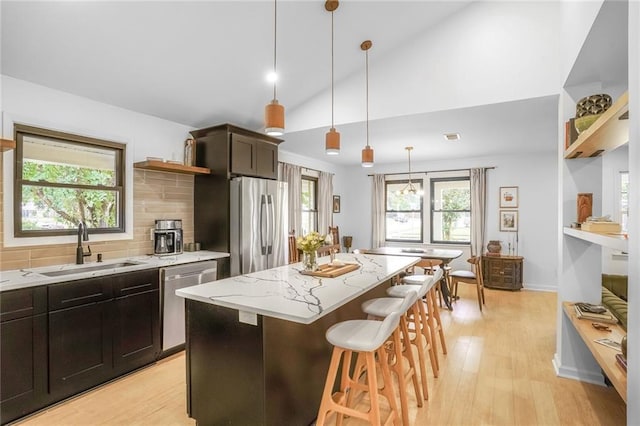 601 Andrews Ave, Metairie, LA 70005 - kitchen with open shelves, stainless steel appliances, a sink, light wood-style flooring, and a breakfast bar area