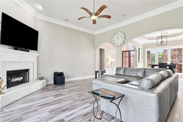 1037 Scarlet Oak Ln, Mandeville, LA 70448 - living room featuring crown molding, light wood-style floors, arched walkways, a ceiling fan, and baseboards