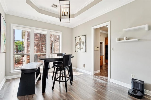 1037 Scarlet Oak Ln, Mandeville, LA 70448 - dining room featuring a chandelier, wood finished floors, crown molding, baseboards, and a raised ceiling