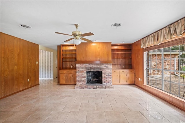 213 N Jayson Dr, Slidell, LA 70458 - unfurnished living room with wood walls, a ceiling fan, built in shelves, a fireplace, and baseboards