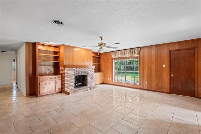 213 N Jayson Dr, Slidell, LA 70458 - unfurnished living room with ceiling fan, a fireplace, wood walls, and a textured ceiling