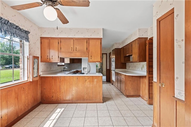 213 N Jayson Dr, Slidell, LA 70458 - kitchen featuring a sink, a peninsula, light countertops, brown cabinets, and wallpapered walls