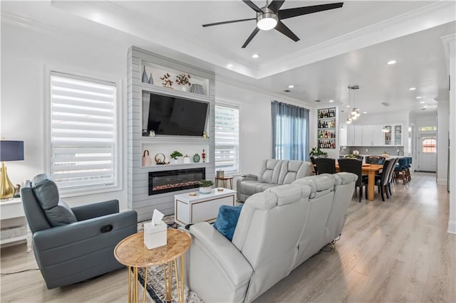 2828 Mistletoe St, New Orleans, LA 70118 - living area with a tray ceiling, ceiling fan, a fireplace, light wood finished floors, and ornamental molding