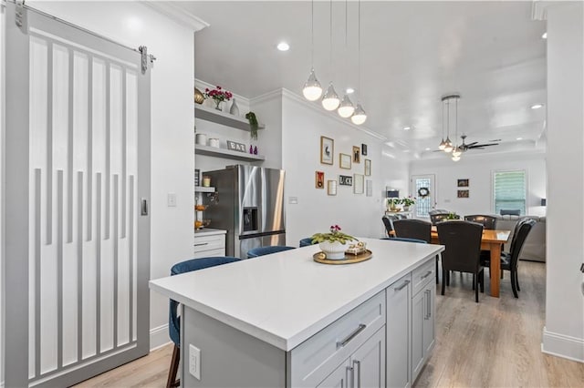2828 Mistletoe St, New Orleans, LA 70118 - kitchen with stainless steel fridge, light countertops, light wood-type flooring, ceiling fan, and crown molding