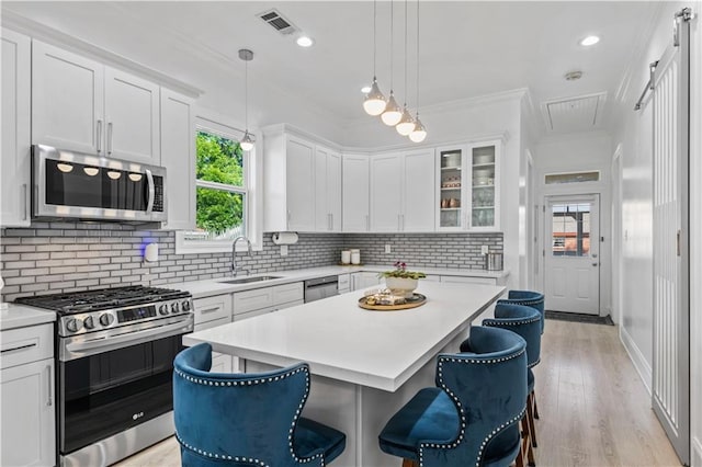 2828 Mistletoe St, New Orleans, LA 70118 - kitchen featuring appliances with stainless steel finishes, a sink, a kitchen breakfast bar, light countertops, and white cabinets
