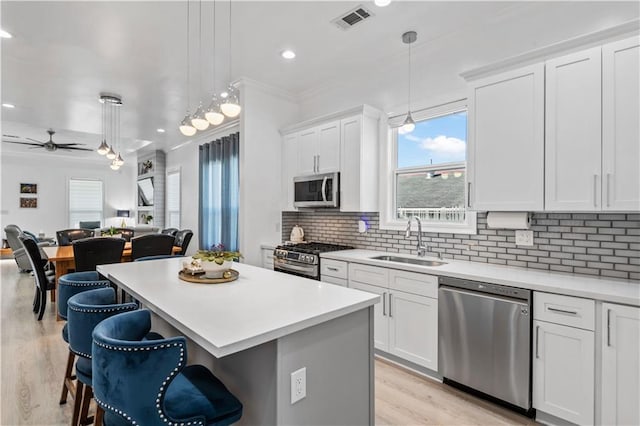 2828 Mistletoe St, New Orleans, LA 70118 - kitchen featuring appliances with stainless steel finishes, a sink, light wood-style flooring, a kitchen island, and open floor plan