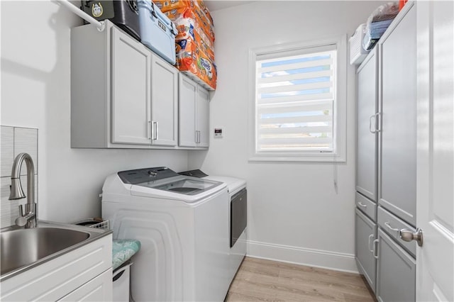 2828 Mistletoe St, New Orleans, LA 70118 - laundry area with cabinet space, washer and clothes dryer, light wood-style flooring, and baseboards