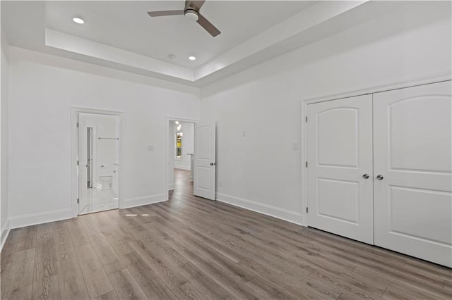 3414 Monroe St, New Orleans, LA 70118 - unfurnished bedroom with a tray ceiling, wood finished floors, baseboards, ensuite bathroom, and recessed lighting