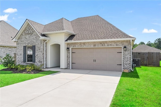 22039 Giselle Dr, Mandeville, LA 70471 - french country style house with an attached garage, concrete driveway, a shingled roof, central AC unit, and brick siding