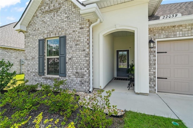 22039 Giselle Dr, Mandeville, LA 70471 - doorway to property featuring a garage, roof with shingles, brick siding, concrete driveway, and stone siding