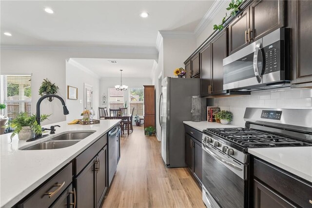 22039 Giselle Dr, Mandeville, LA 70471 - kitchen featuring appliances with stainless steel finishes, a sink, light countertops, a chandelier, and crown molding
