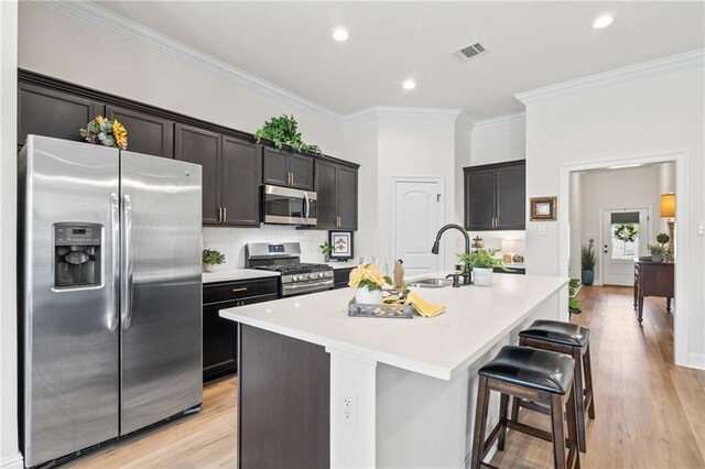 22039 Giselle Dr, Mandeville, LA 70471 - kitchen featuring stainless steel appliances, a sink, ornamental molding, a center island with sink, and light countertops