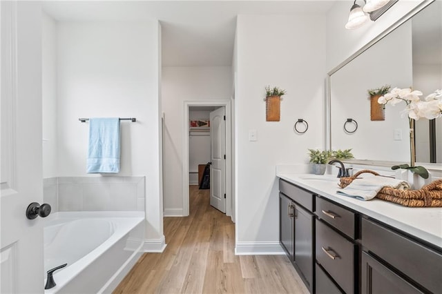 22039 Giselle Dr, Mandeville, LA 70471 - full bathroom with vanity, wood finished floors, a garden tub, baseboards, and a walk in closet