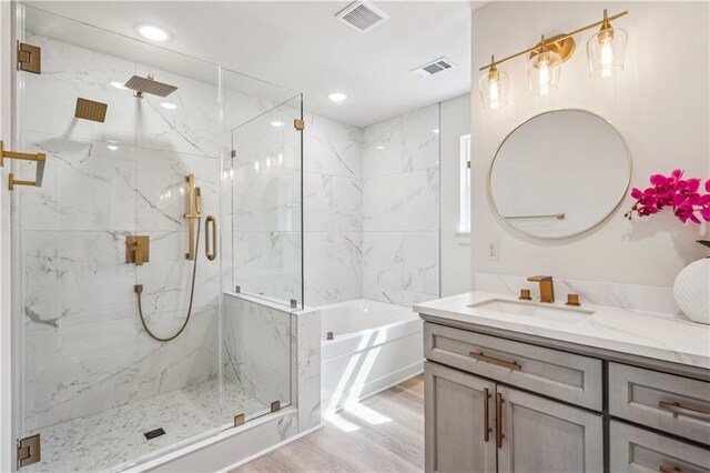 21507 Birtrue Rd, Bush, LA 70431 - bathroom featuring vanity, a garden tub, a marble finish shower, wood finished floors, and recessed lighting