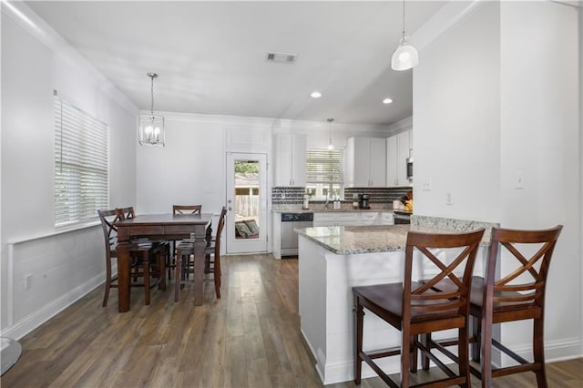 1951 Beth Dr, Slidell, LA 70458 - kitchen with stainless steel dishwasher, tasteful backsplash, dark wood-style floors, white cabinets, and a peninsula