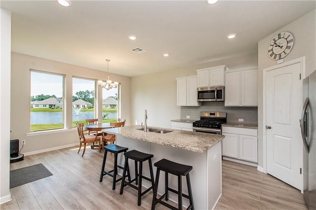 40262 Sedgwick Ln, Ponchatoula, LA 70454 - kitchen featuring stainless steel appliances, a chandelier, decorative backsplash, light stone counters, and a center island with sink