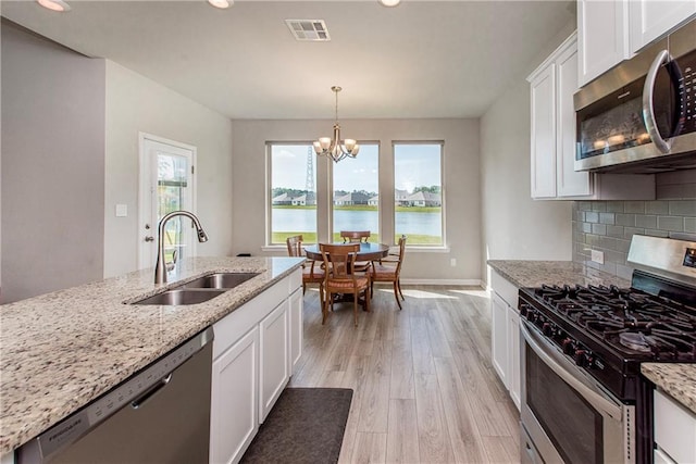 40262 Sedgwick Ln, Ponchatoula, LA 70454 - kitchen with appliances with stainless steel finishes, light wood finished floors, a chandelier, white cabinets, and recessed lighting