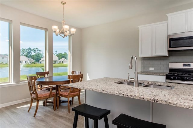 40262 Sedgwick Ln, Ponchatoula, LA 70454 - kitchen featuring stainless steel appliances, light stone countertops, white cabinets, tasteful backsplash, and light wood finished floors