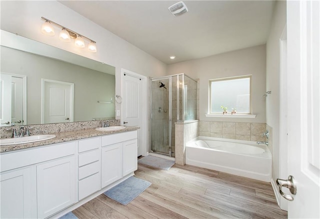 40262 Sedgwick Ln, Ponchatoula, LA 70454 - bathroom featuring a stall shower, a bath, double vanity, and wood finished floors