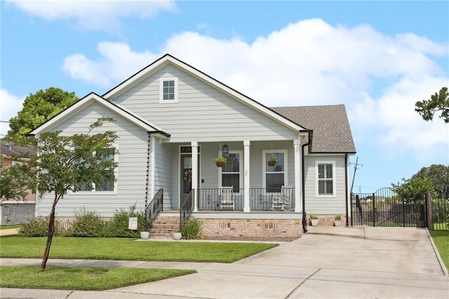 1908 Alexander Ave, Arabi, LA 70032 - view of front of home with a porch, driveway, a front yard, a gate, and roof with shingles