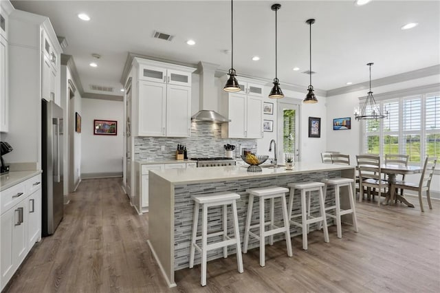 1908 Alexander Ave, Arabi, LA 70032 - kitchen with wall chimney exhaust hood, stainless steel refrigerator, light countertops, tasteful backsplash, and a breakfast bar area