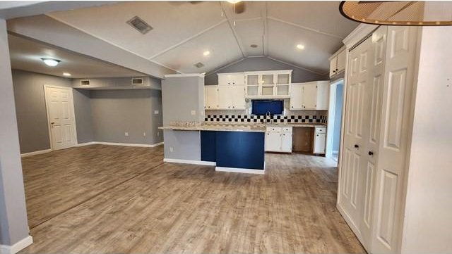 146 Elodie Ave, Harahan, LA 70123 - kitchen featuring white cabinets, light countertops, baseboards, backsplash, and vaulted ceiling
